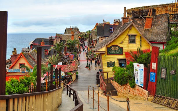 Street view of colorful wooden buildings in Popeye Village, Malta, near the sea.