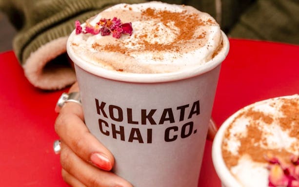 Kolkata Chai Co. cup with chai topped with spices and flowers.