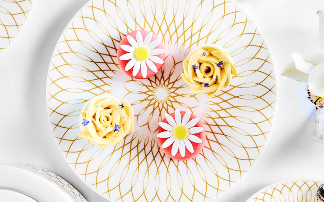 Cupcakes with floral designs on a decorative plate at Pearl Afternoon Tea, Platos.