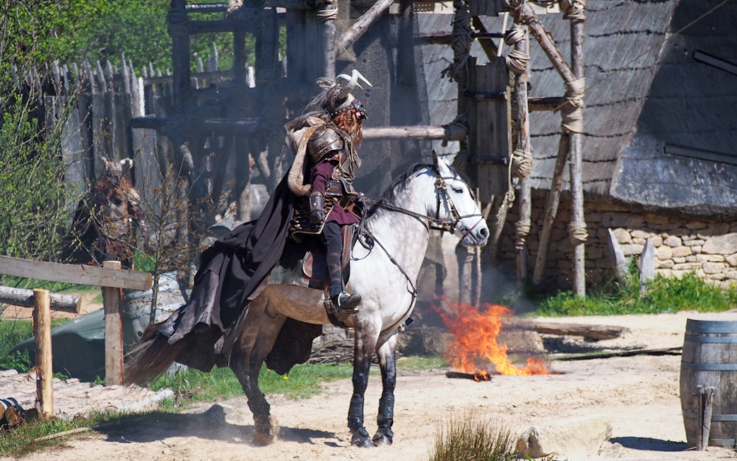 Medieval knight on horseback at Puy du Fou with fire in the background.
