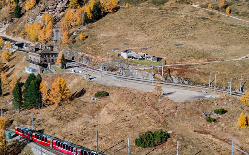 Red train traveling through Swiss Alps on a scenic route, Switzerland Interrail pass.