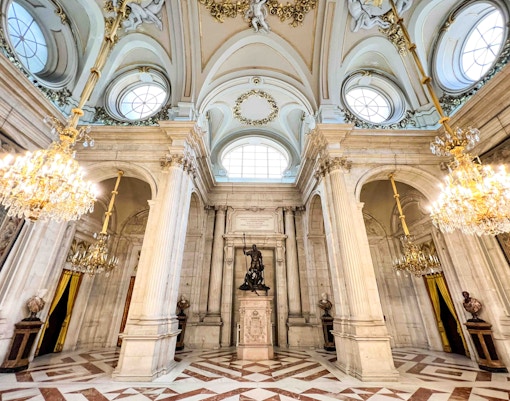 Royal Palace of Madrid entrance with tourists exploring the historic architecture.