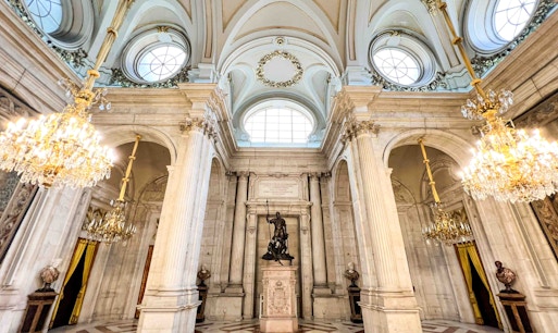 Royal Palace of Madrid entrance with tourists exploring the historic architecture.