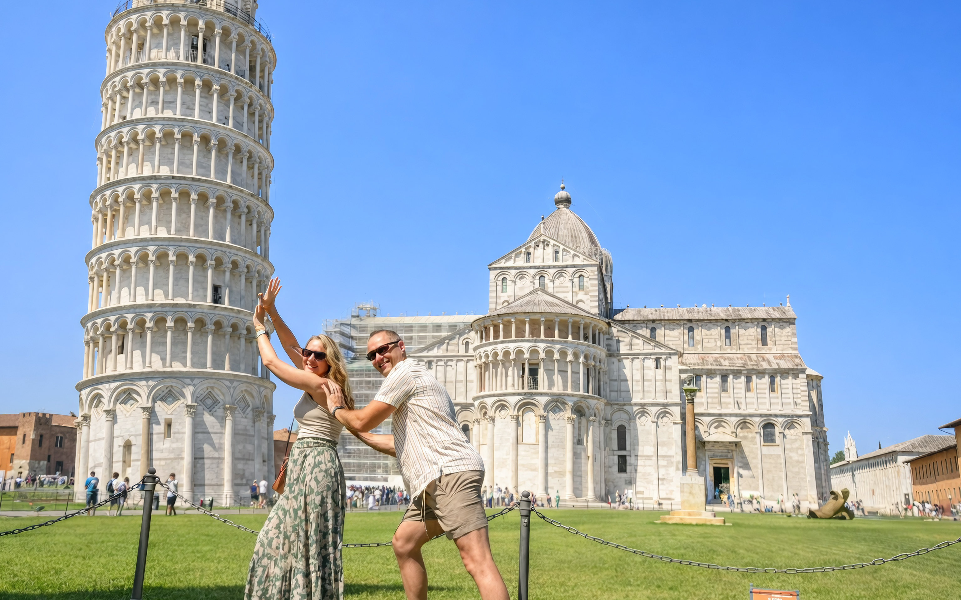 Couple posing playfully in front of the Leaning Tower of Pisa, Italy.