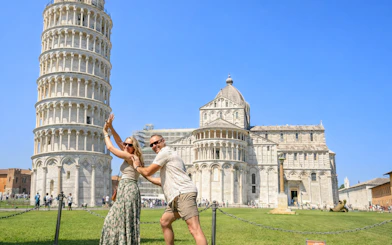 Couple posing playfully in front of the Leaning Tower of Pisa, Italy.