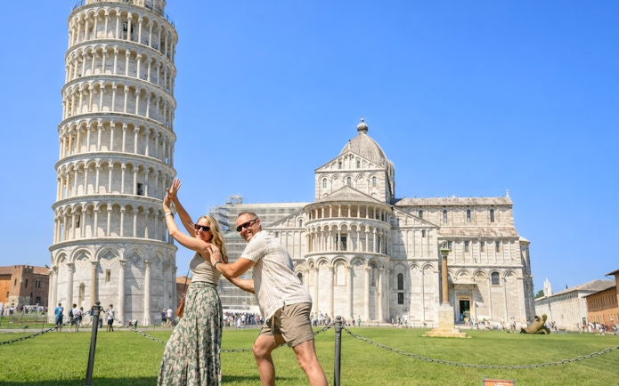 Couple posing playfully in front of the Leaning Tower of Pisa, Italy.