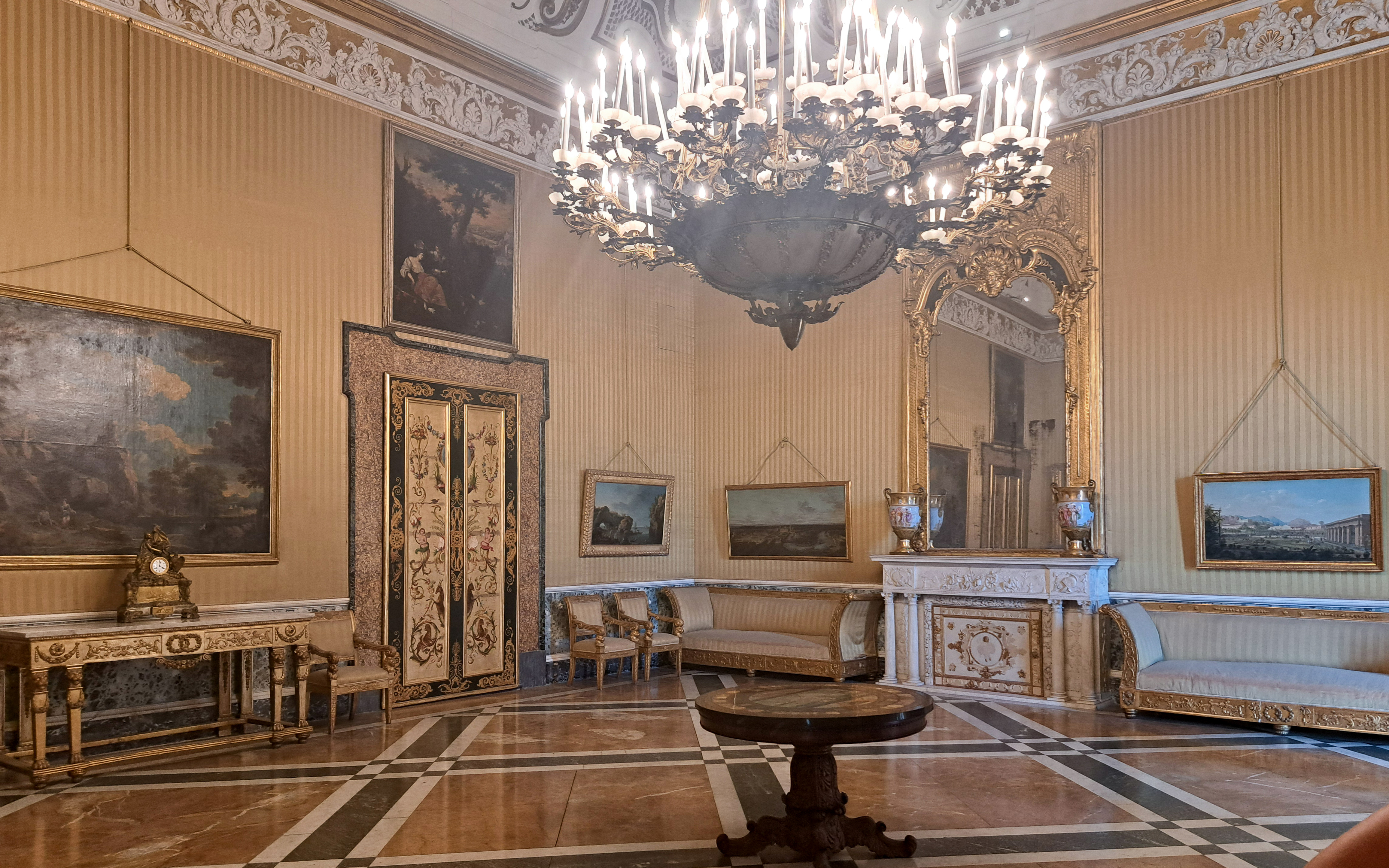 Royal Palace of Naples interior with ornate chandelier, paintings, and decorative furniture.