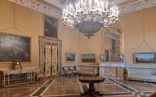 Royal Palace of Naples interior with ornate chandelier, paintings, and decorative furniture.