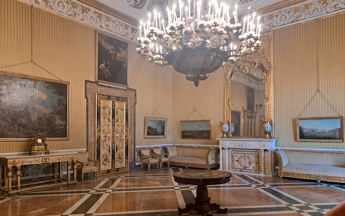 Royal Palace of Naples interior with ornate chandelier, paintings, and decorative furniture.