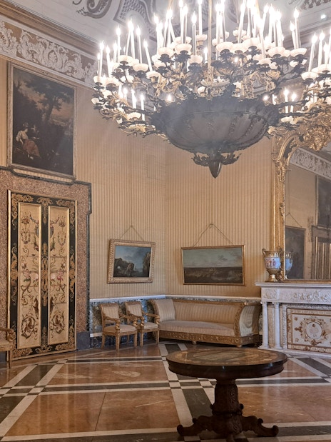 Royal Palace of Naples interior with ornate chandelier, paintings, and decorative furniture.