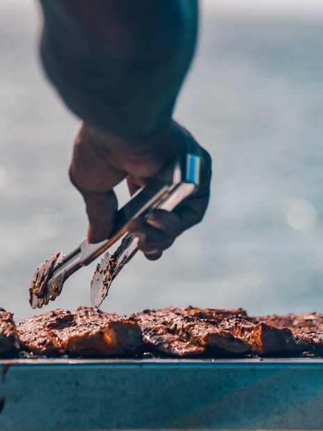 Grilling meat on a cruise boat with ocean in the background.