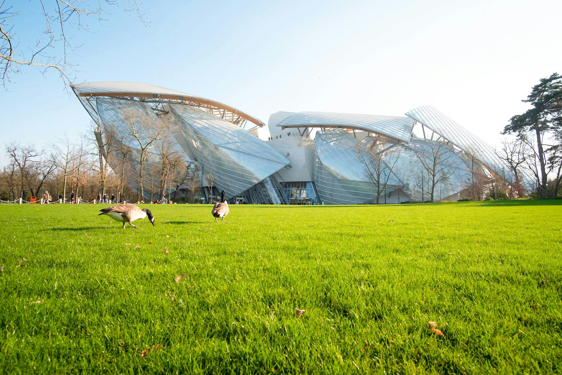 Fondation Louis Vuitton building with glass panels and green lawn in Paris.