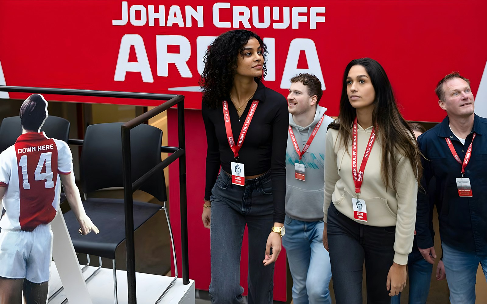 Visitors on Johan Cruijff ArenA Classic Tour wearing lanyards, near stadium seating.