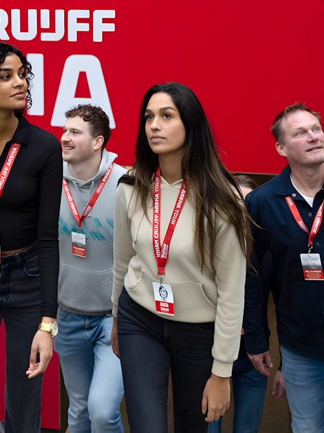 Visitors on Johan Cruijff ArenA Classic Tour wearing lanyards, near stadium seating.