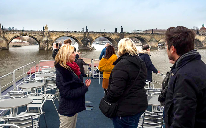 Prague boat cruise with tourists viewing Charles Bridge.