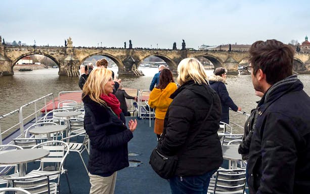 Prague boat cruise with tourists viewing Charles Bridge.
