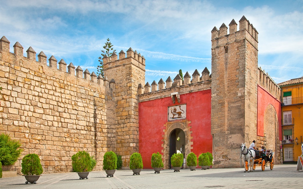 Tourists in a horse-drawn carriage at the entrance of Alcazar of Seville, Spain.