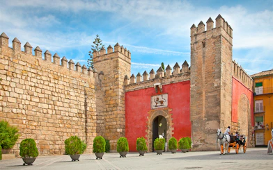 Tourists in a horse-drawn carriage at the entrance of Alcazar of Seville, Spain.