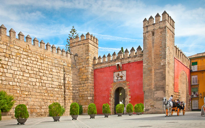 Tourists in a horse-drawn carriage at the entrance of Alcazar of Seville, Spain.