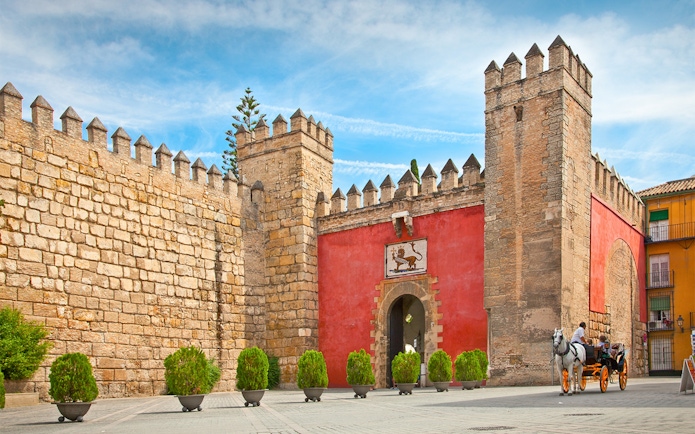 Tourists in a horse-drawn carriage at the entrance of Alcazar of Seville, Spain.