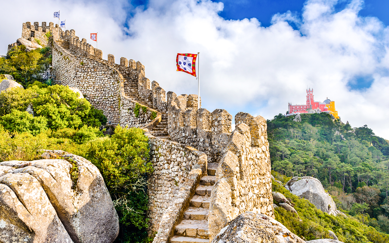 Moorish Castle walls with view of colorful Pena Palace in Sintra, Portugal.
