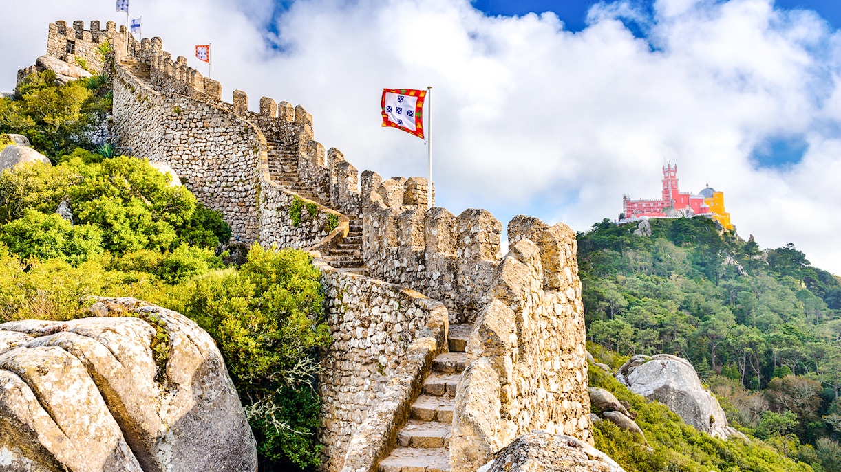 Moorish Castle walls with view of colorful Pena Palace in Sintra, Portugal.
