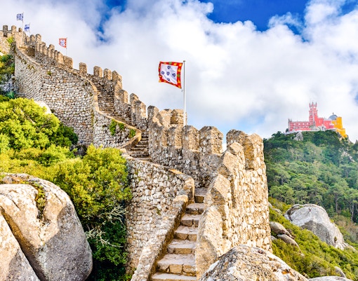 Moorish Castle walls with view of colorful Pena Palace in Sintra, Portugal.