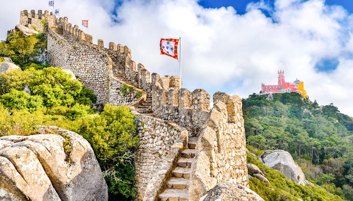 Moorish Castle walls with view of colorful Pena Palace in Sintra, Portugal.