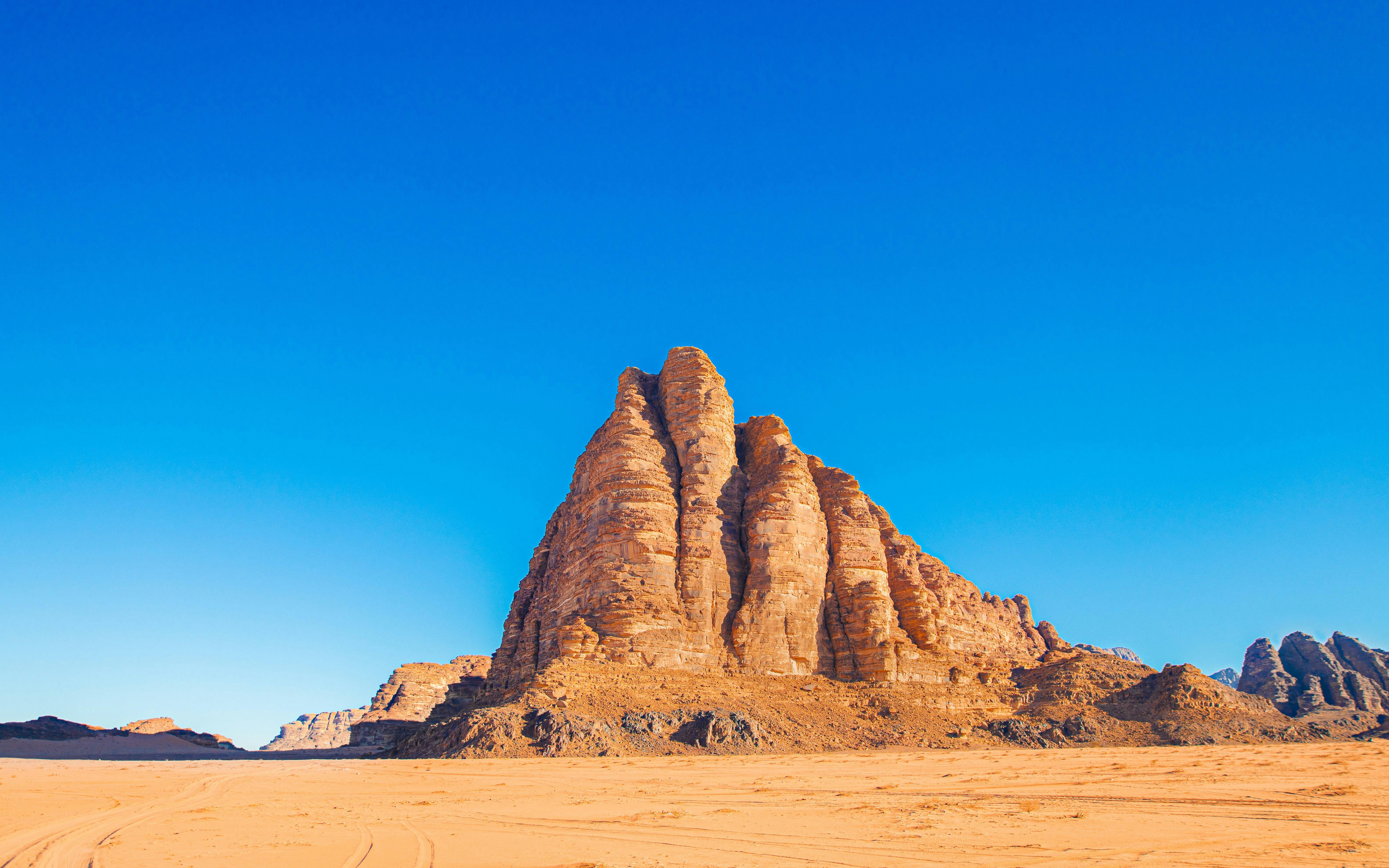 Seven Pillars of Wisdom rock formation under blue sky, Wadi Rum, Jordan.