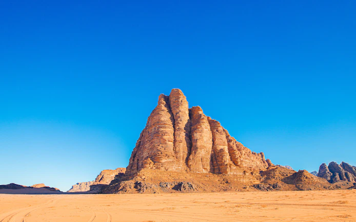 Seven Pillars of Wisdom rock formation under blue sky, Wadi Rum, Jordan.