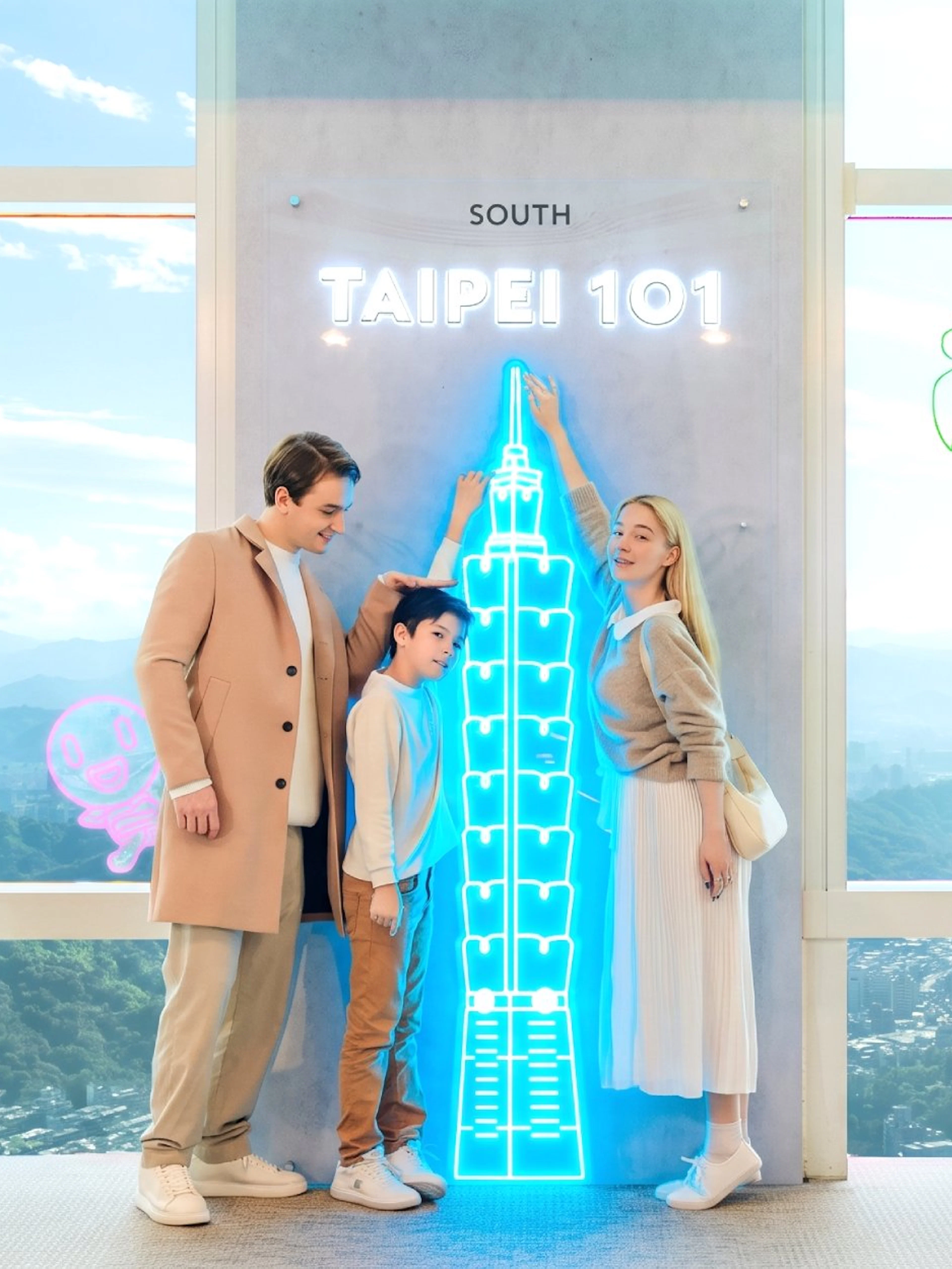 Family enjoying Taipei 101 Observatory with neon skyline display.