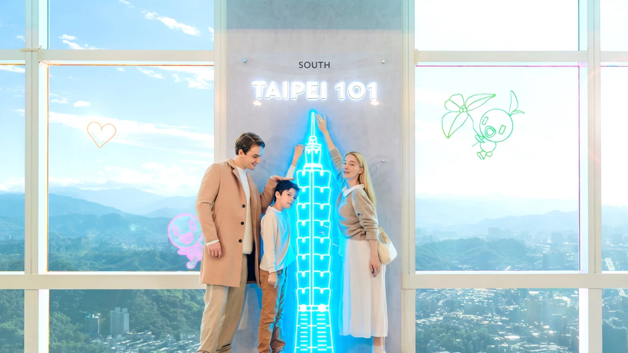 Family enjoying Taipei 101 Observatory with neon skyline display.