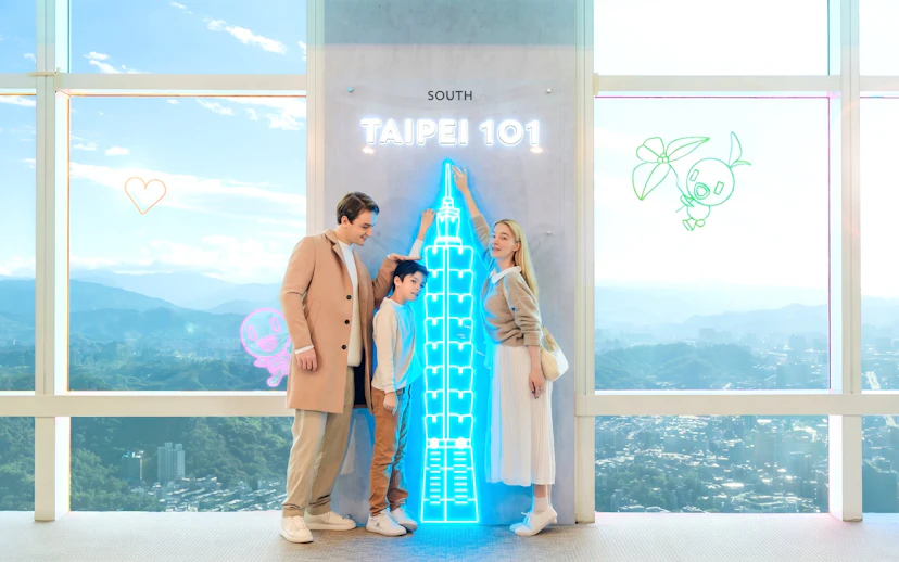 Family enjoying Taipei 101 Observatory with neon skyline display.