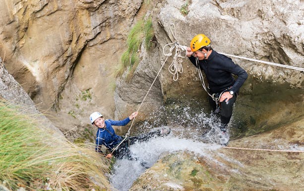 Canyoning participants navigating a waterfall in Chli Schliere near Interlaken.
