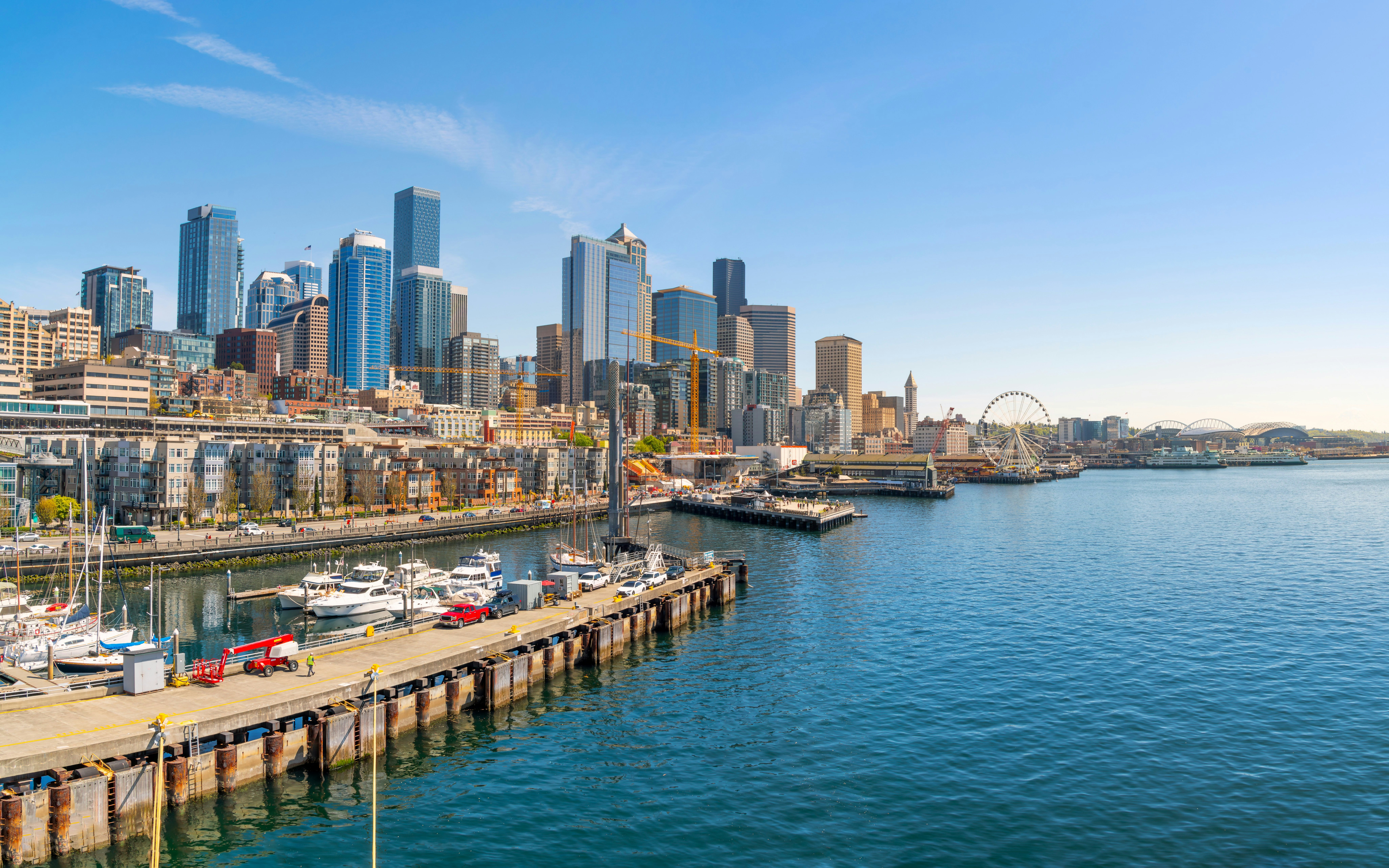 Seattle harbor with skyline, featuring skyscrapers and waterfront ferris wheel.