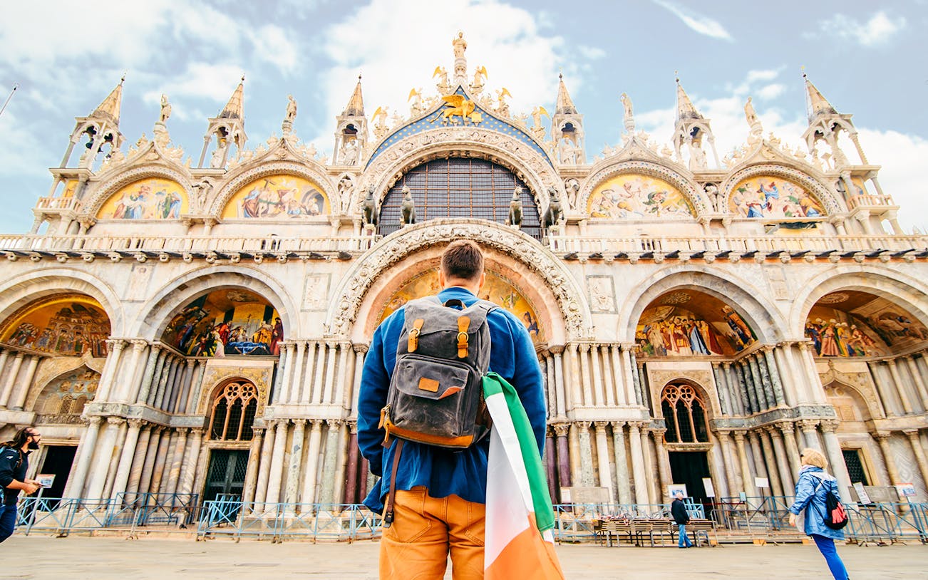 Man holding Italian flag in front of St. Mark's Basilica, Venice.