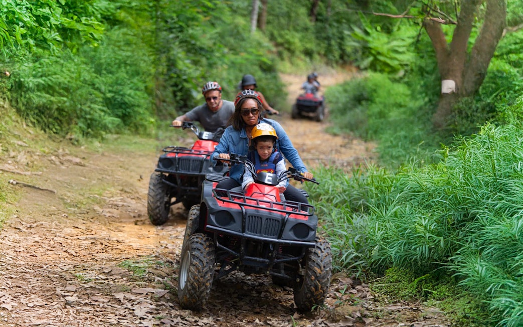 Tourists riding ATVs through lush green trails near Phuket.