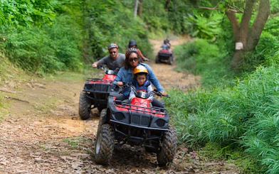 Tourists riding ATVs through lush green trails near Phuket.