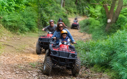 Tourists riding ATVs through lush green trails near Phuket.