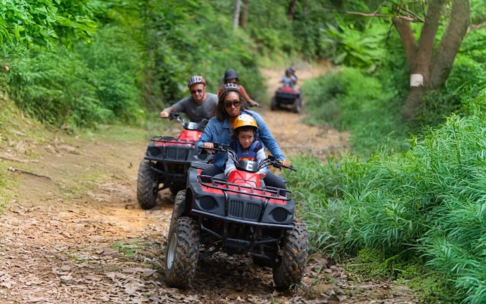 Tourists riding ATVs through lush green trails near Phuket.