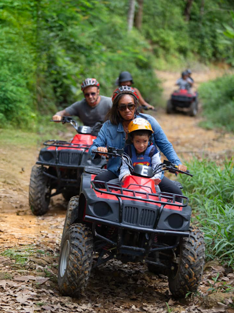 Tourists riding ATVs through lush green trails near Phuket.