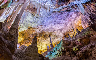 Stalactites and stalagmites inside Drach Caves, Mallorca, with colorful lighting.