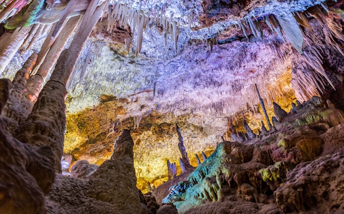 Stalactites and stalagmites inside Drach Caves, Mallorca, with colorful lighting.