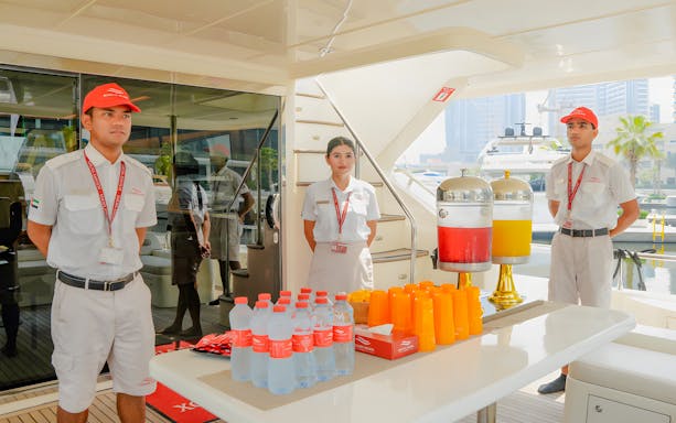 Yacht crew members with drinks ready to serve guests in Dubai.