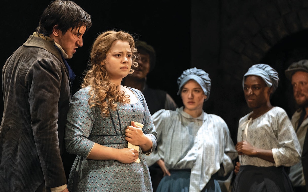 Actors performing a scene from Les Miserables on stage.