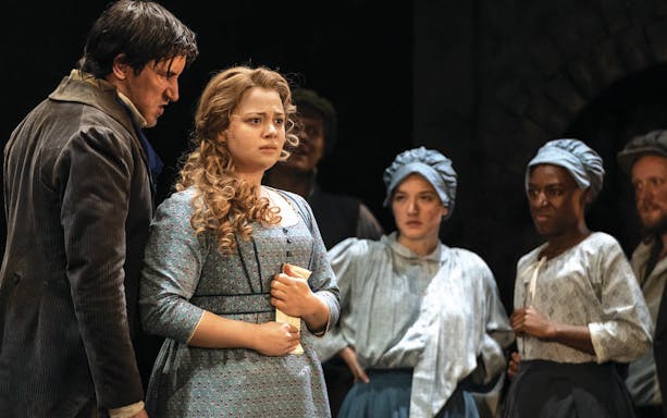 Actors performing a scene from Les Miserables on stage.