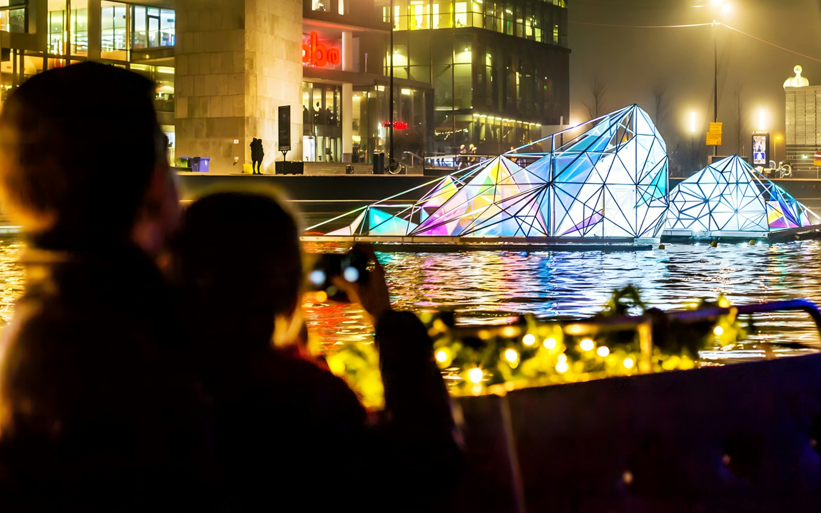 Guests viewing illuminated art installation on Amsterdam Light Festival Cruise.