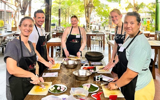 Participants chopping ingredients at Nia Balinese Cooking Class in an outdoor setting.