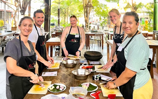 Participants chopping ingredients at Nia Balinese Cooking Class in an outdoor setting.