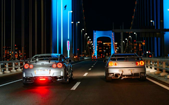 Two sports cars on a Tokyo bridge at night during JDM car meetup tour.